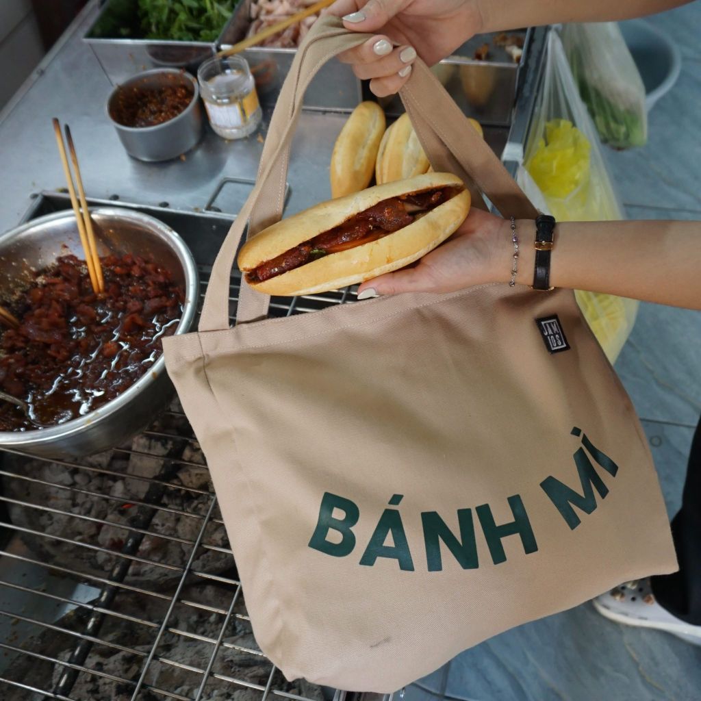 6-tren-tui-canvas-in-chu-banh-mi-tung-net-chu-toat-len-su-tuoi-vui-phong-khoang-nhu-chinh-cach-nguoi-viet-mang-o-banh-mi-nong-hoi-tren-tay-thuong-thuc-giua-nhip-song-soi-dong