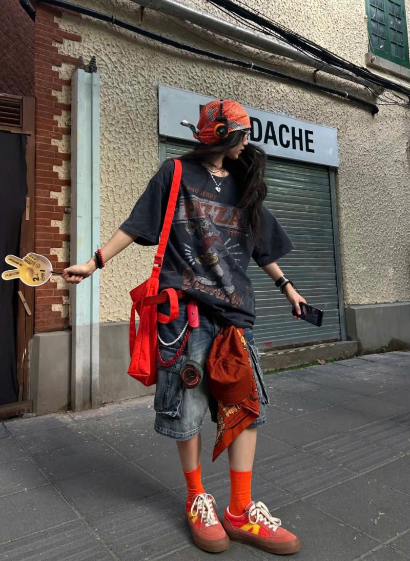 Áo thun graphic oversize đen phối quần short jeans và phụ kiện màu cam nổi bật