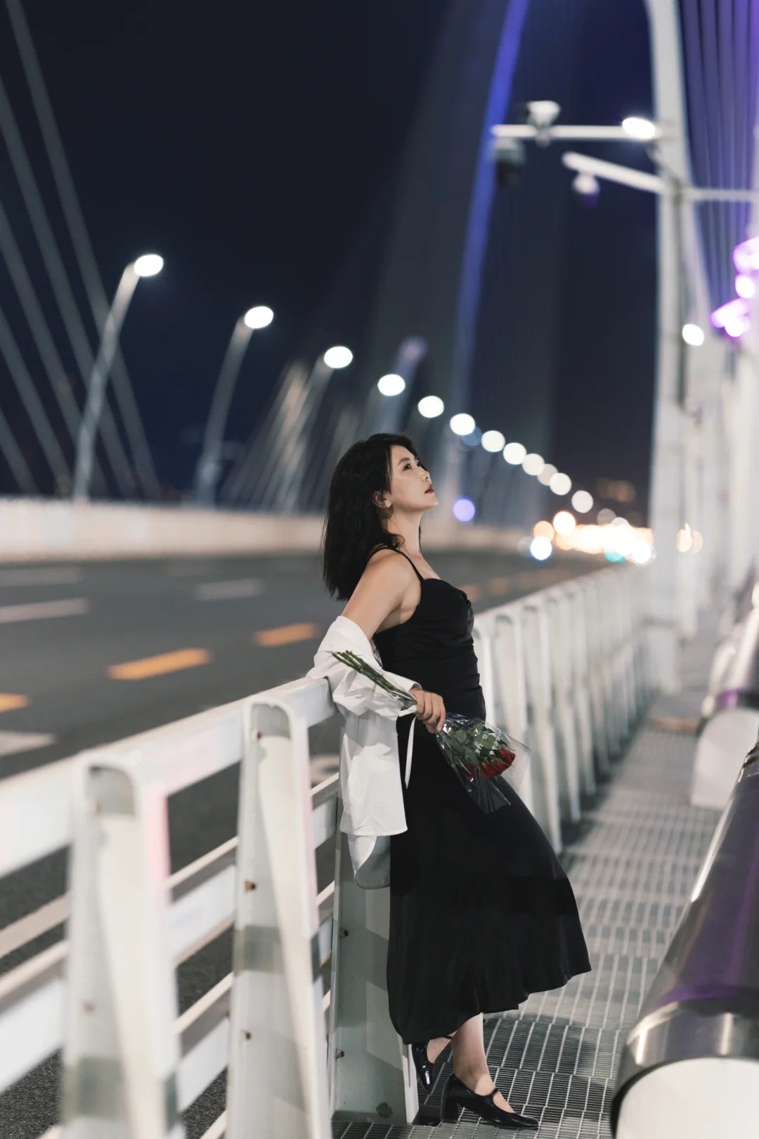 18. Tư thế đứng dựa lan can buổi tối, tay cầm hoa