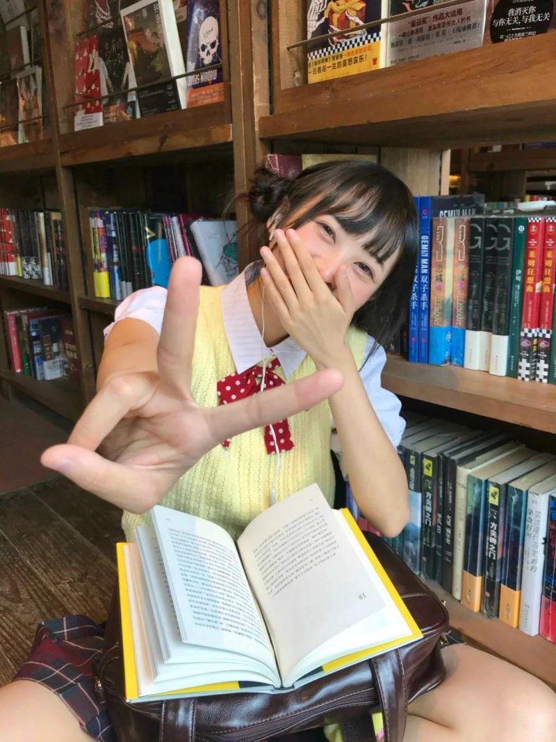 (lấp ló sau hàng sách, biểu cảm vui tươi)