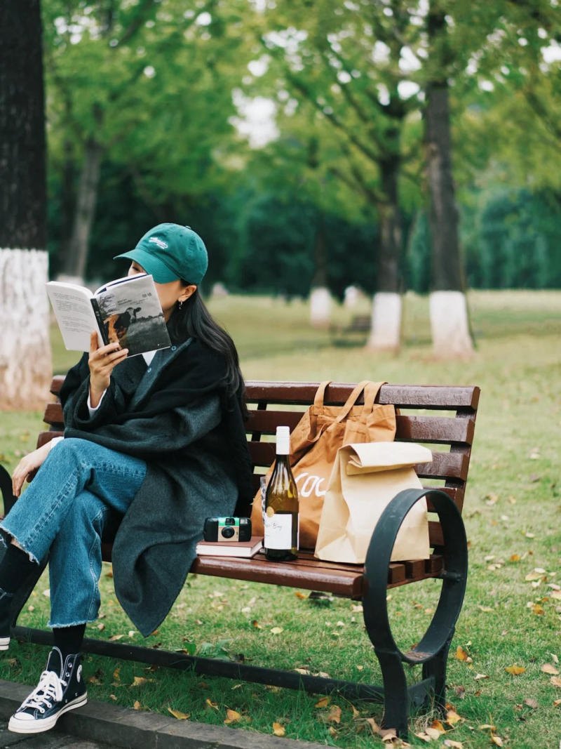 (đội mũ, ngồi vắt chéo chân, đọc sách)