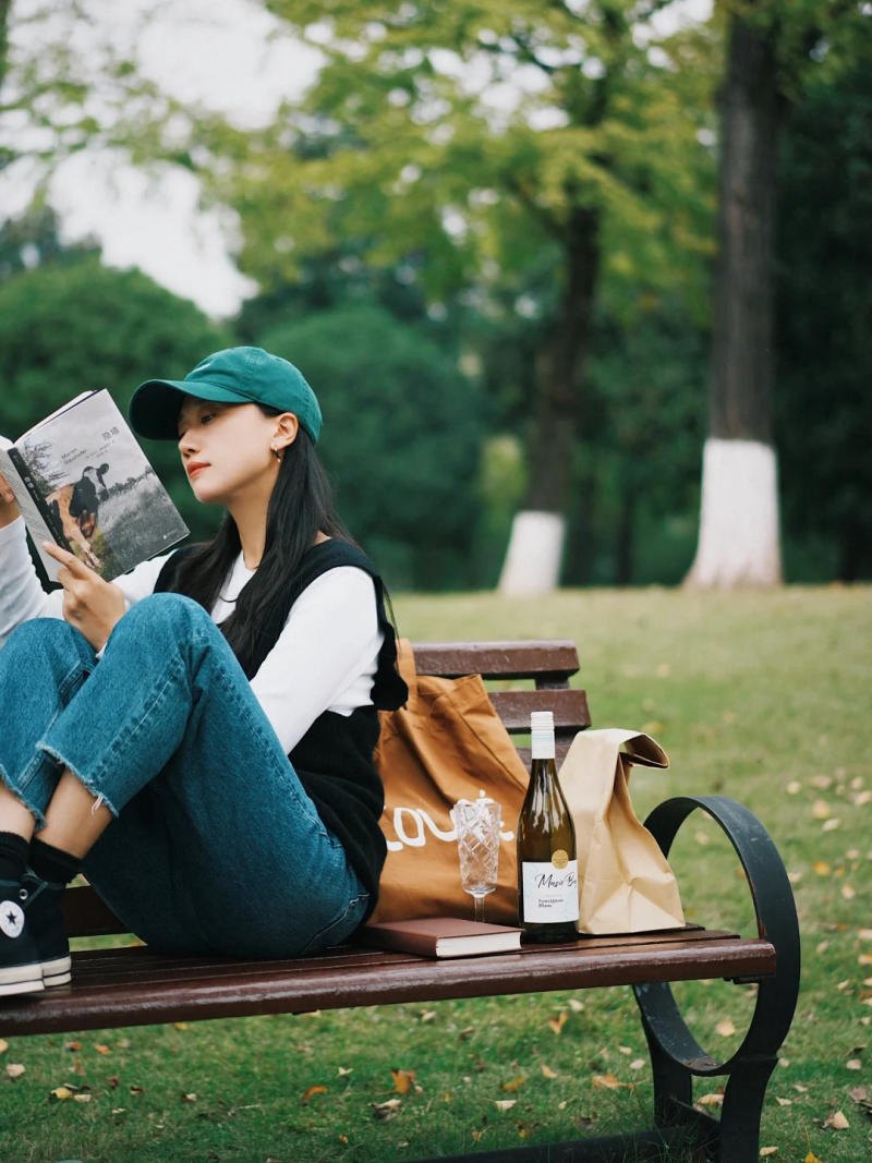 (dựa lưng vào kệ, cúi đầu nhìn sách)