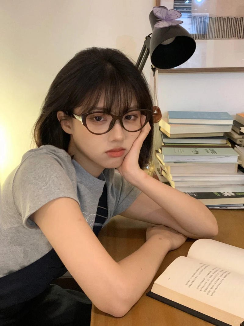 (tay chống cằm, mắt nhìn thẳng, sách mở)