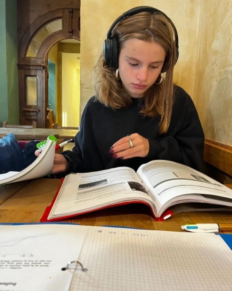 (dựa lưng vào kệ sách, tay cầm sách che mặt)