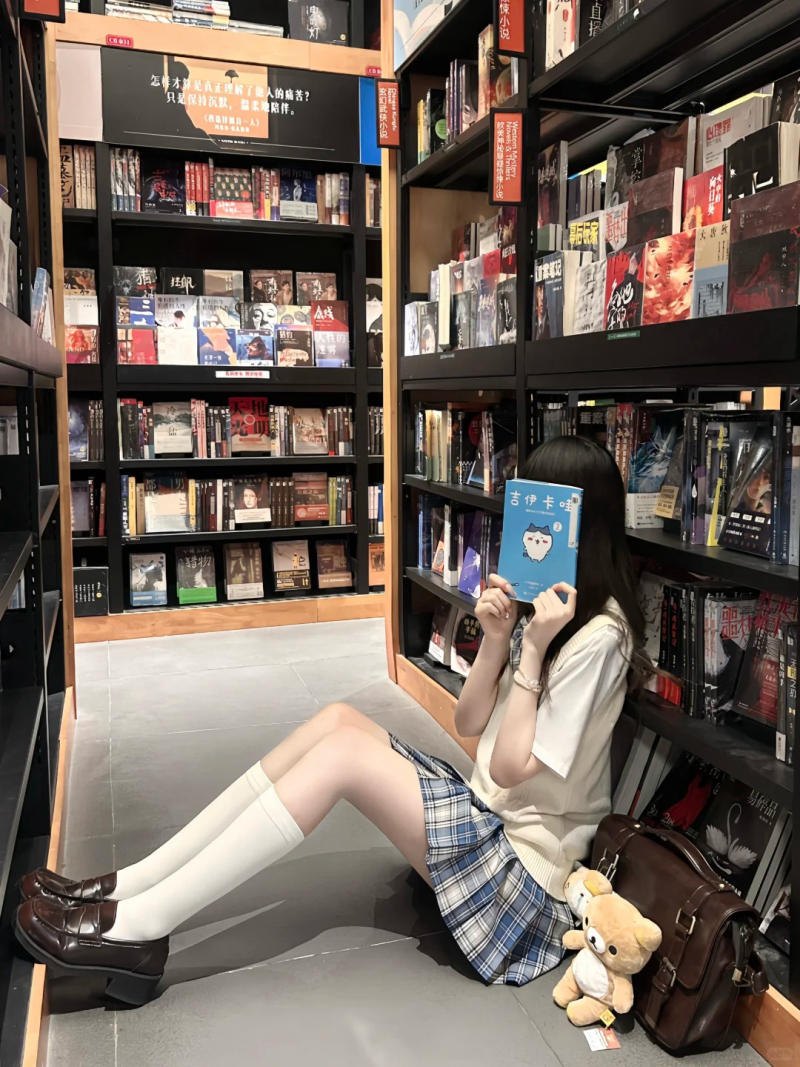 (dựa lưng vào kệ sách, tay cầm sách che mặt)