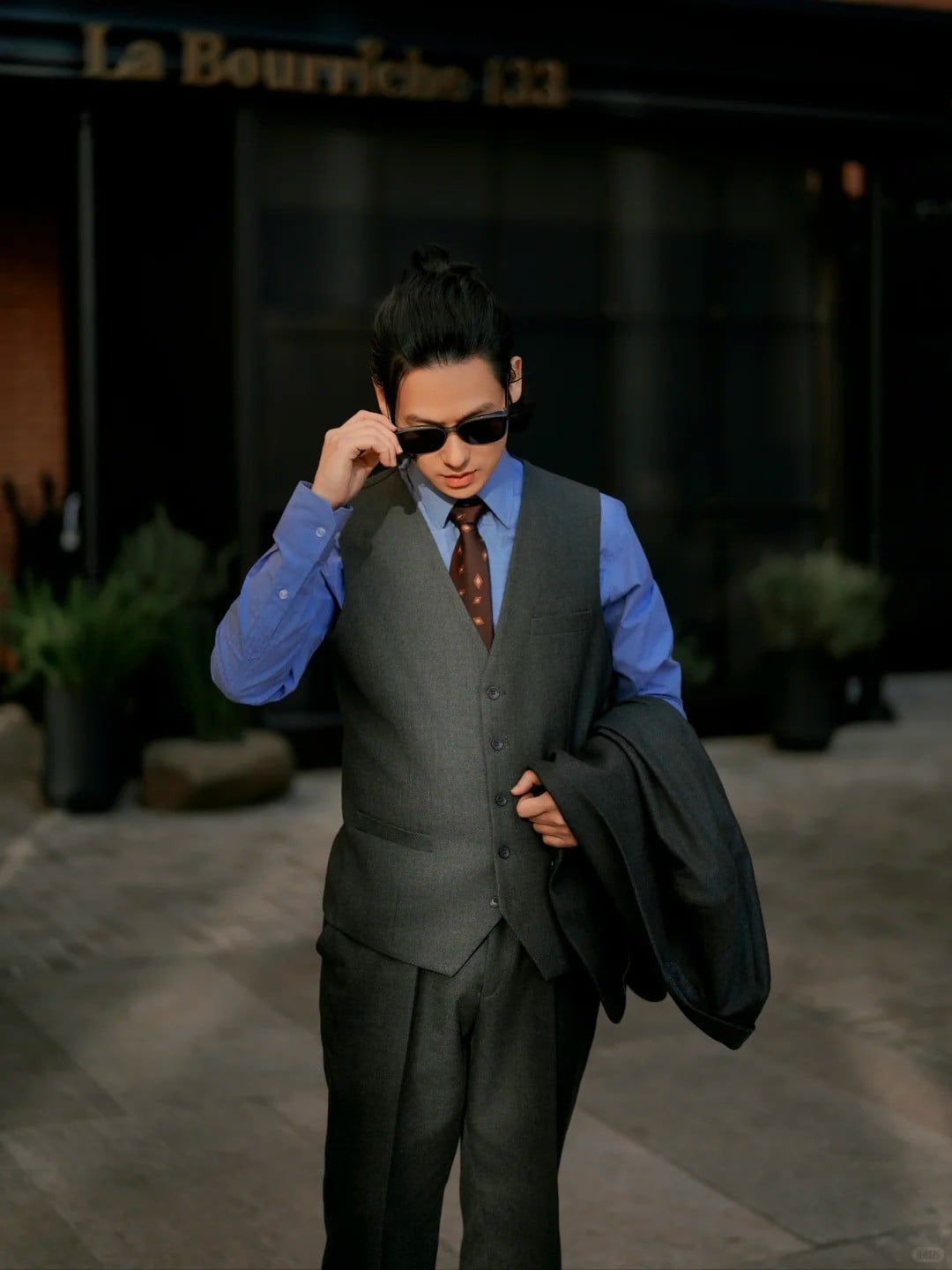 1. Tư thế chỉnh kính râm, tay cầm áo khoác