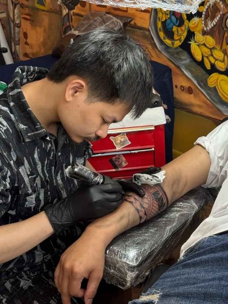 Nghệ nhân xăm đang thực hiện hình xăm tả thực với đường nét tỉ mỉ