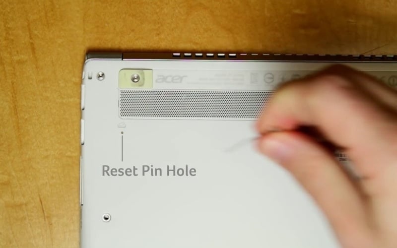 Dùng que chọc sim ấn vào lỗ nhỏ biểu tượng viên pin ở mặt đáy và giữ trong 10 giây