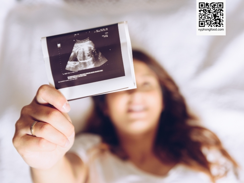 Pregnant woman reading a guide about how to drink multi grains cereal safely by pregnancy stage - Greenmax prenatal cereal advice from vyphongfood.com.