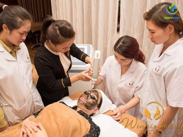 Lớp học thực hành laser kỹ thuật cao tại Winnie beauty ACADEMY, một địa chỉ học phun xăm và thẩm mỹ uy tín. Bác sĩ hướng dẫn trực tiếp cho học viên áo blouse trắng trên khách hàng đắp mặt nạ carbon.