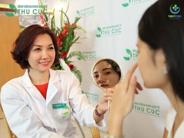 Bác sĩ Bệnh viện Thu Cúc mỉm cười cầm gương soi phân tích vết nám cho khách hàng tại địa chỉ trị nám uy tín