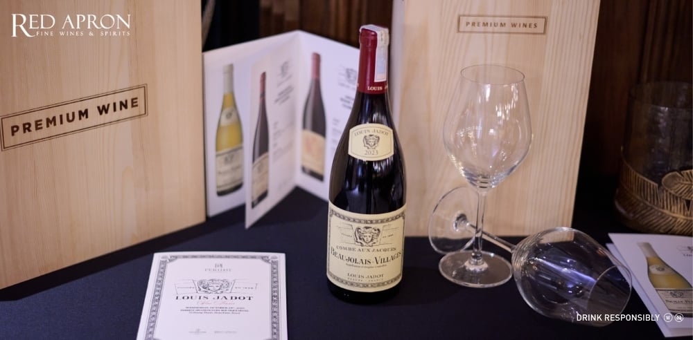 Khu trưng bày rượu vang Maison Louis Jadot tại Red Apron với chai vang đỏ và ly rượu, minh họa phong cách Louis Jadot Beaujolais-Villages tươi mát, dễ uống, phù hợp cho tiệc đứng và buổi gặp gỡ thân mật.