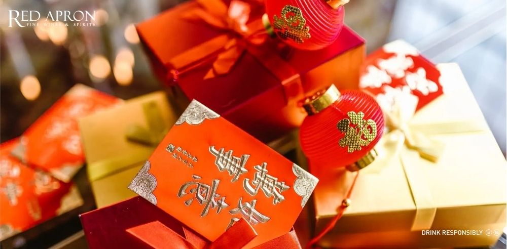 Hộp quà gói giấy đỏ vàng kèm bao lì xì và phụ kiện trang trí Tết, minh họa lưu ý khi chọn quà Tết cho bố mẹ.