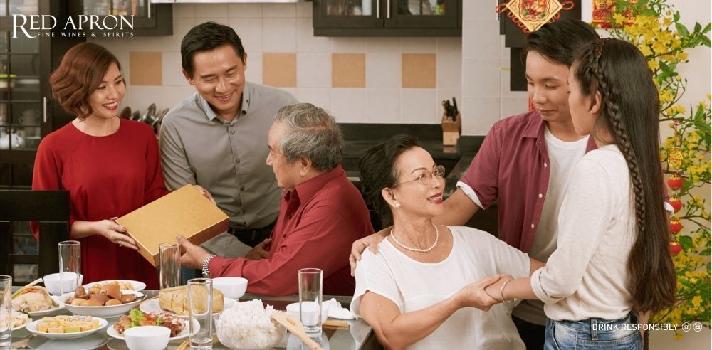 Con gái tặng hộp quà cho bố trong bữa cơm gia đình ngày Tết, minh họa cách tặng quà Tết cho bố mẹ tinh tế.