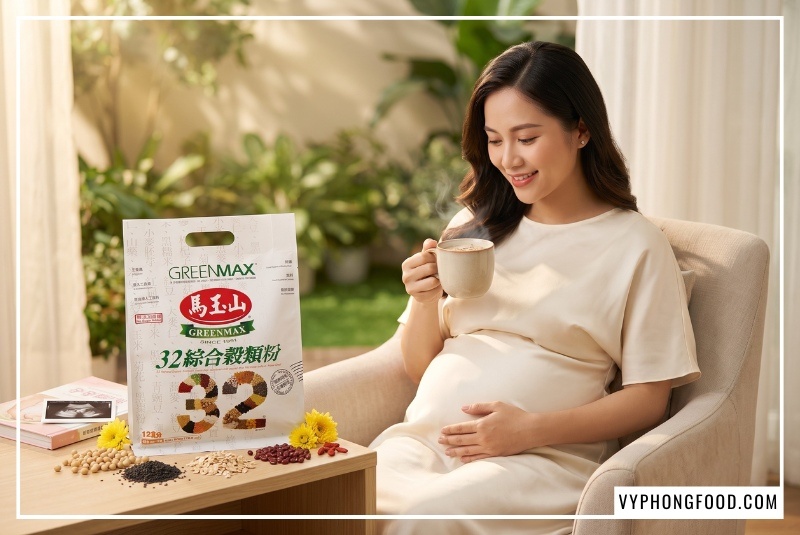 Hình ảnh mẹ bầu Việt Nam trẻ trung đoan trang diện váy lụa kem trang nhã ngồi thư giãn cạnh kệ gỗ bày trí túi bột ngũ cốc không đường Greenmax Đài Loan chính hãng, tay nâng niu ly ngũ cốc ấm áp bốc khói nhẹ rạng rỡ, minh họa trực quan câu hỏi bột ngũ cốc có tốt cho bà bầu không.