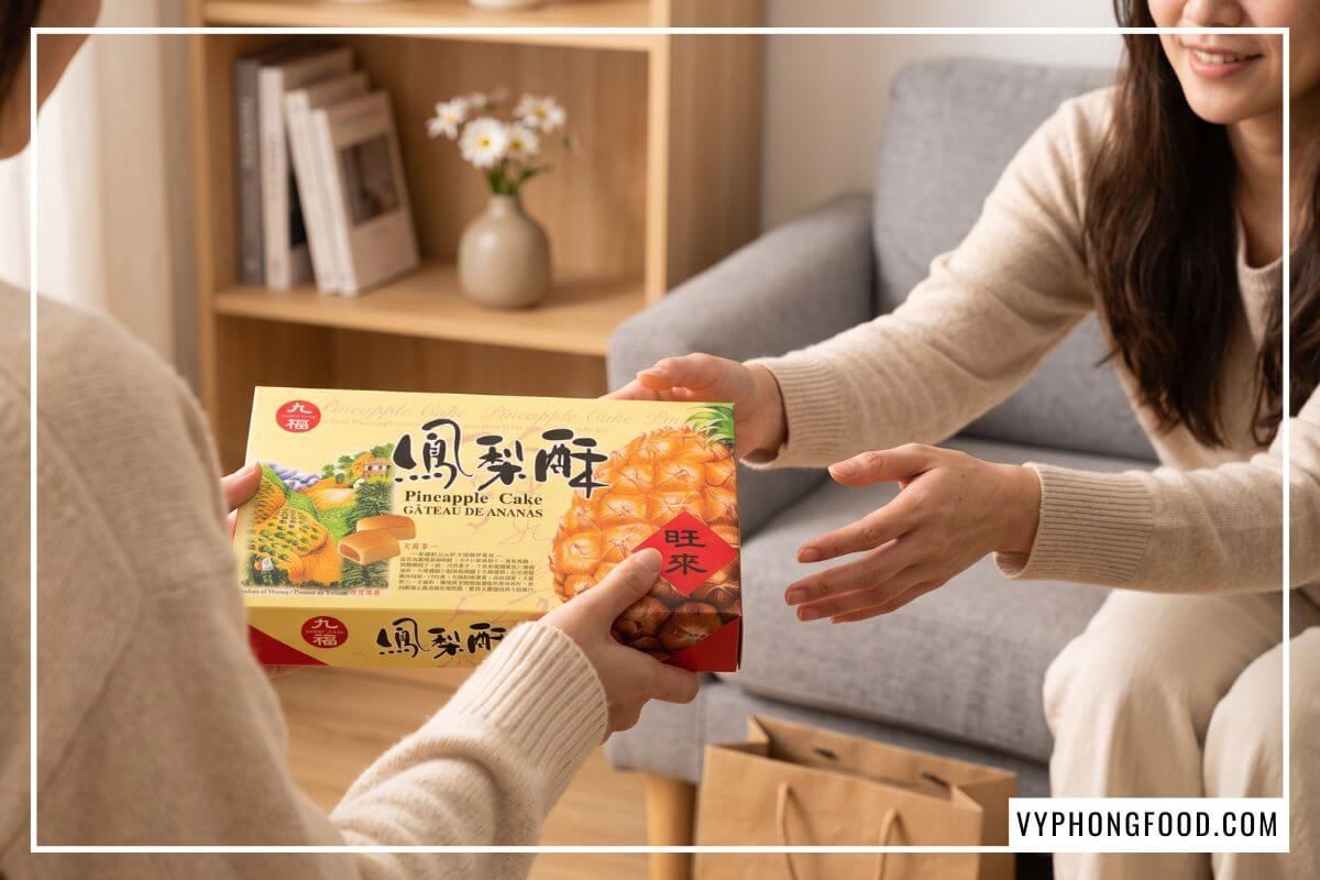 Bàn tay trao tặng hộp bánh dứa Đài Loan Nice Choice nhập khẩu chính hãng trong phòng khách ấm cúng
