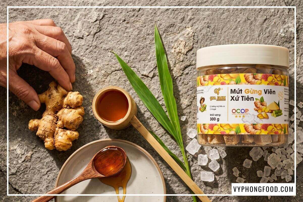 Củ gừng sẻ Tiên Phước tươi bên gáo mạch nha dẻo quánh và hũ mứt gừng viên trên nền đá sa thạch.