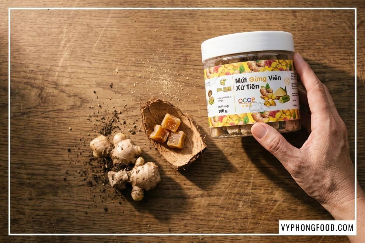 Hũ mứt gừng nắp trắng cạnh củ gừng sẻ trên bàn sồi, món ăn đặc sản Đà Nẵng