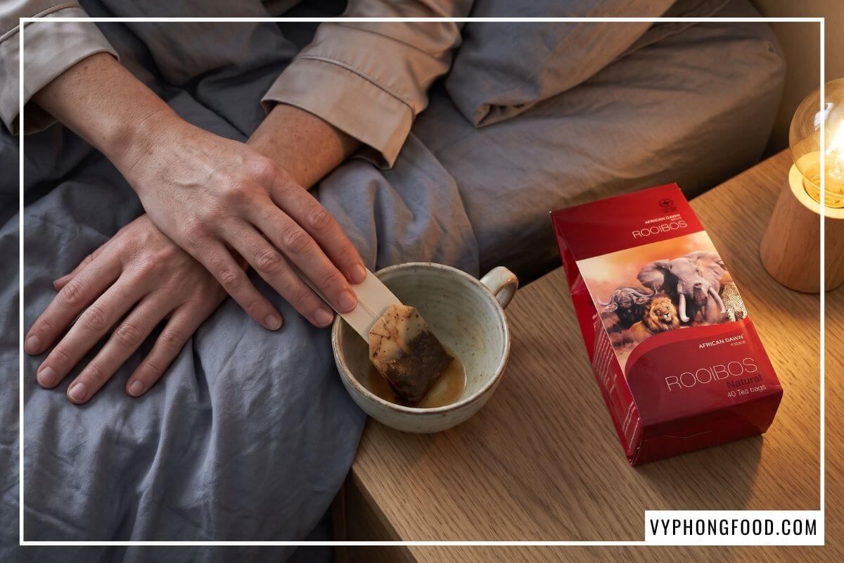 Người đan tay thả lỏng trên giường xám khói sau khi cạn tách trà giảm căng thẳng.