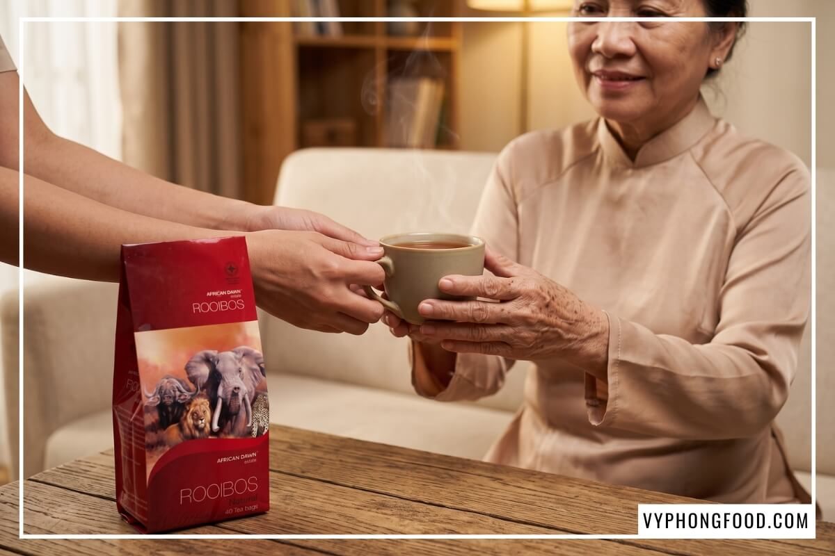 Con gái trao tách trà rooibos Nam Phi an toàn cho sức khỏe màu đỏ hổ phách cho mẹ già.