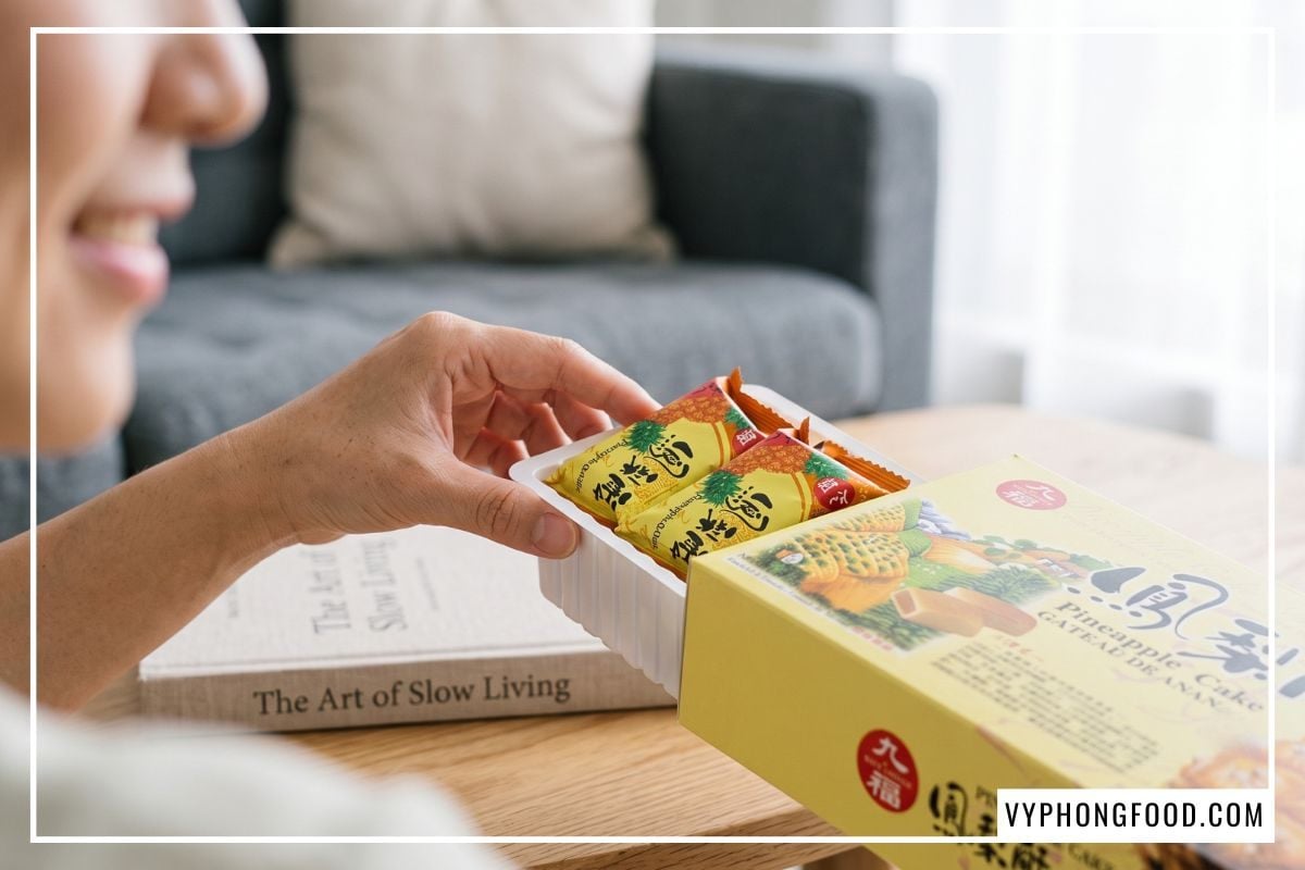 Cô gái mỉm cười rút khay bánh dứa đóng gói túi màng nhôm riêng lẻ từ trong hộp giấy Nice Choice cứng cáp.