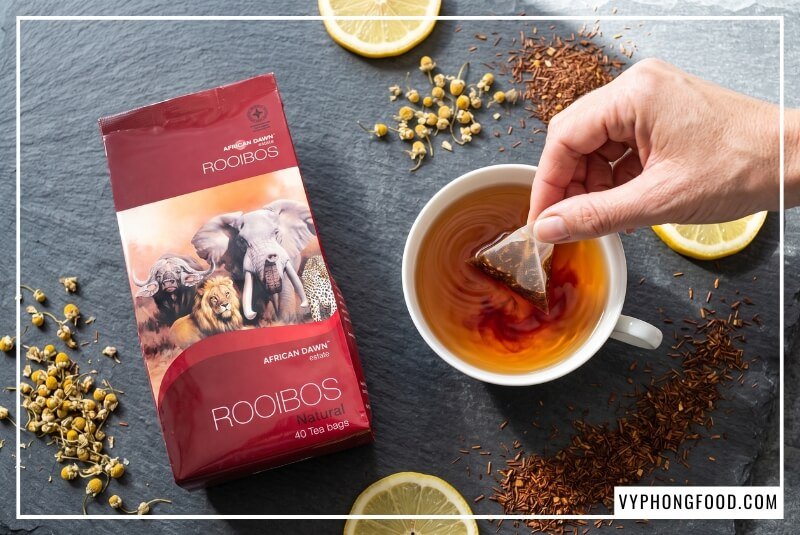 Đôi bàn tay thả túi lọc hồng trà rooibos African Dawn giúp giải đáp uống trà thảo mộc có tốt không cho sức khỏe.