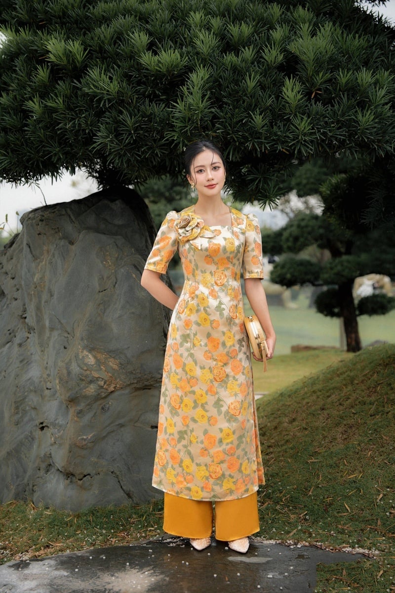 Áo dài cổ vuông gấm hoa vàng cam rực rỡ đính hoa vai