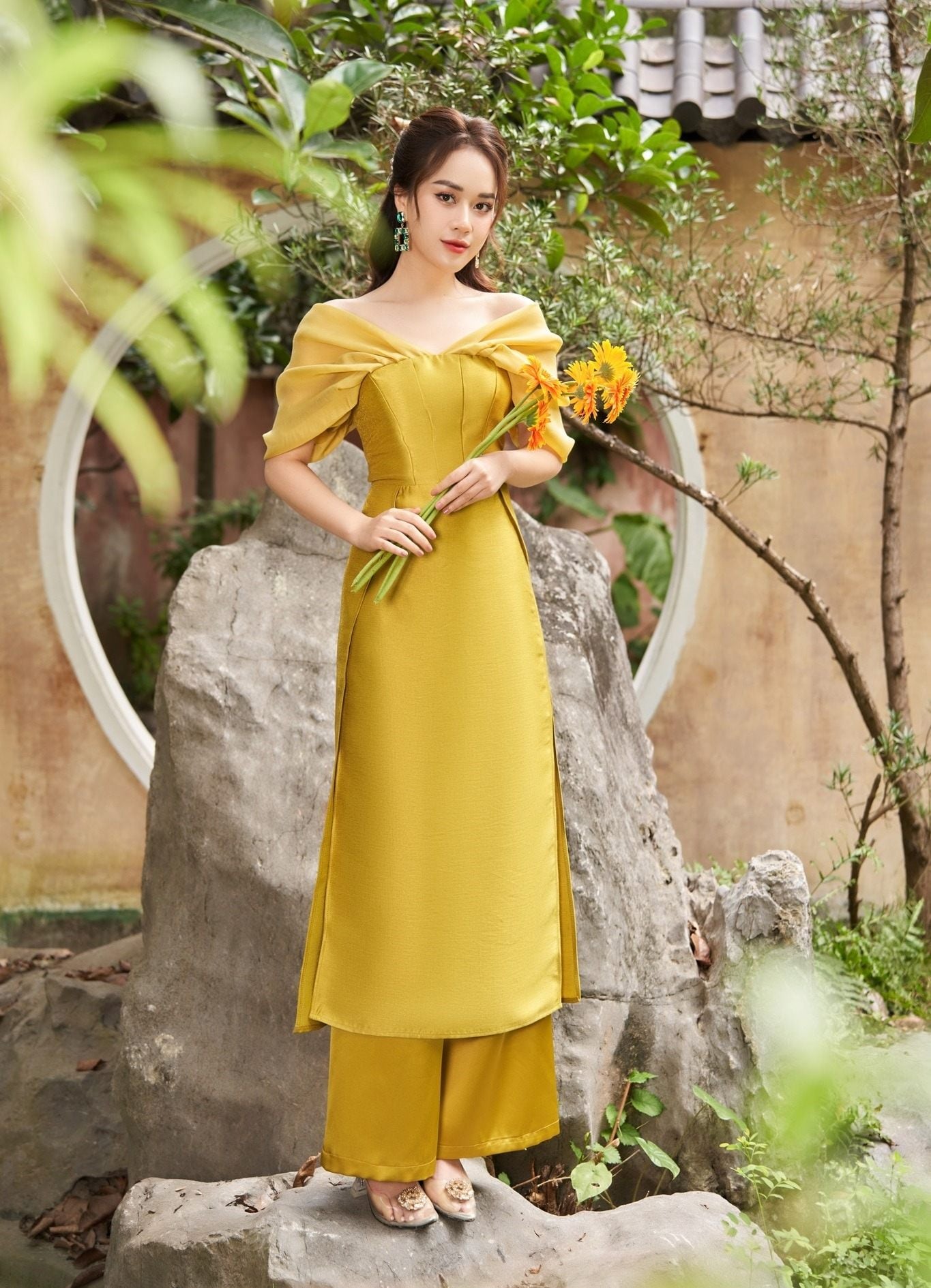 19. Mẫu áo dài vàng mù tạt trễ vai xếp ly tôn dáng