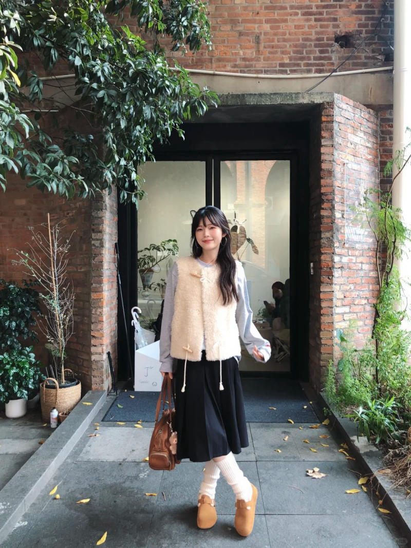 4. Áo gile lông cừu + Chân váy xếp ly đen + Giày Clogs