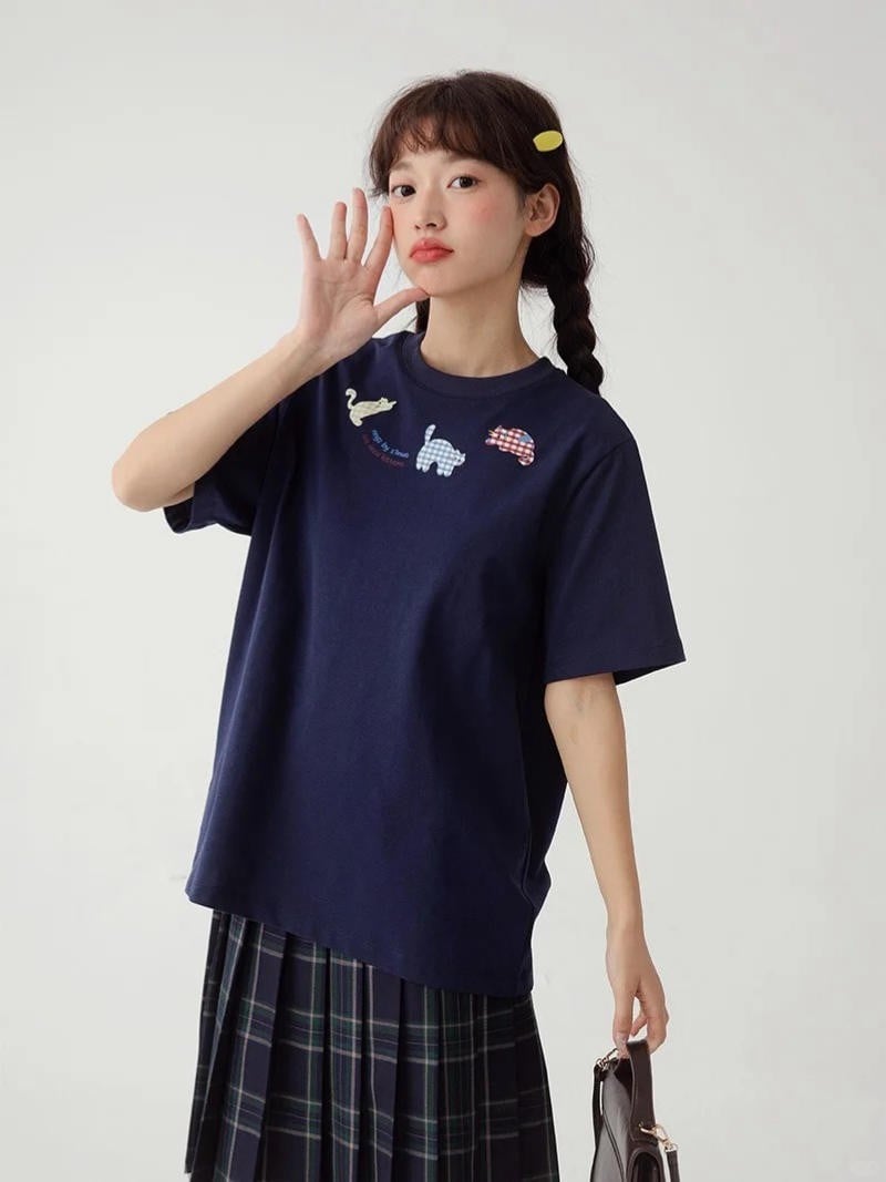 9. Áo thun navy thêu hình nhỏ + Chân váy xếp ly kẻ caro + Túi xách tay