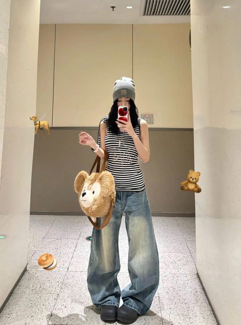 Quần jeans ống cong xanh bạc màu phối đơn giản cùng áo tank top sọc và túi gấu bông