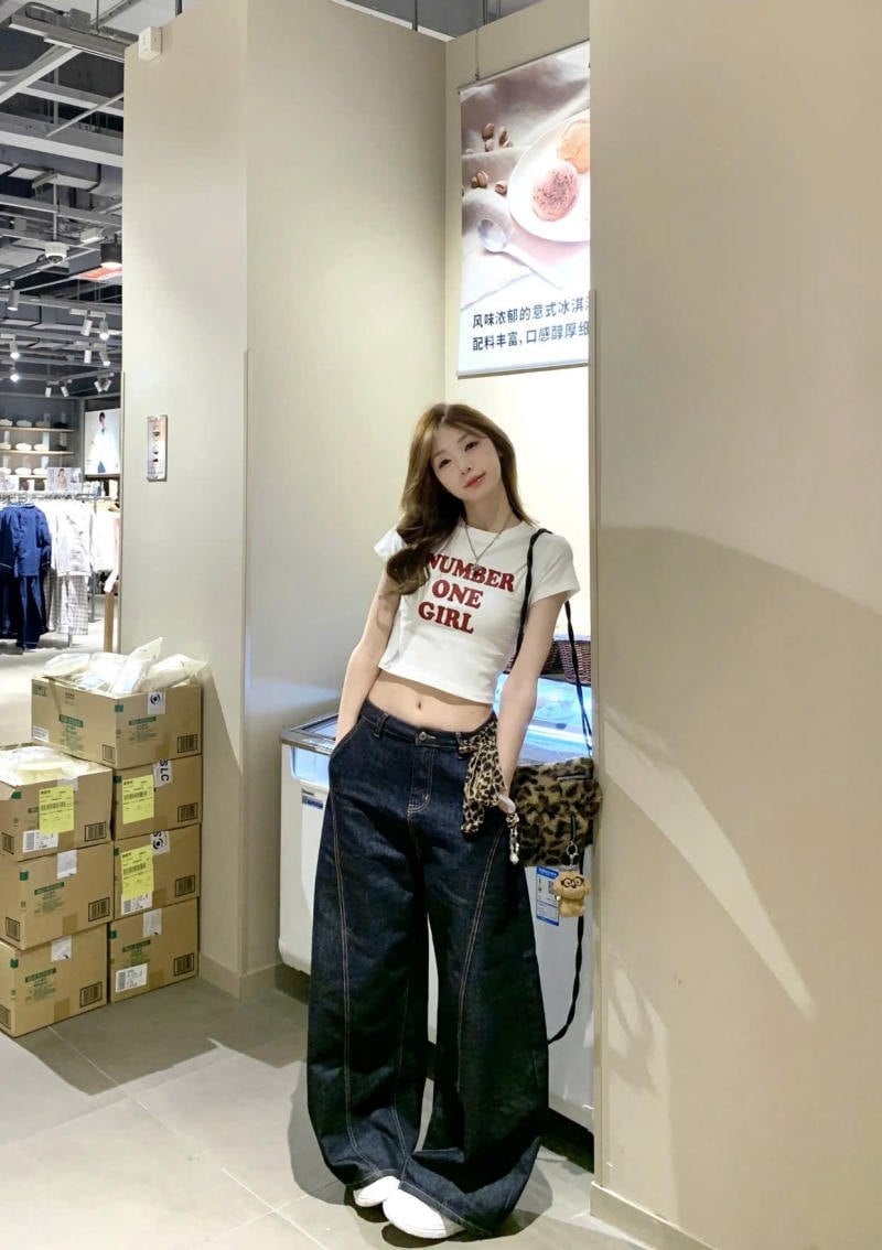 Quần jeans ống cong màu xanh đậm phối năng động cùng áo crop top và túi da báo