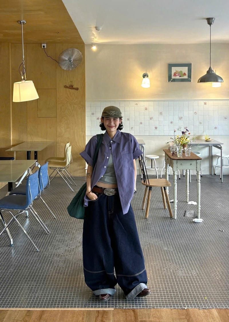 Quần jeans ống cong màu xanh đậm phối cùng áo sơ mi tím và phụ kiện xanh lá