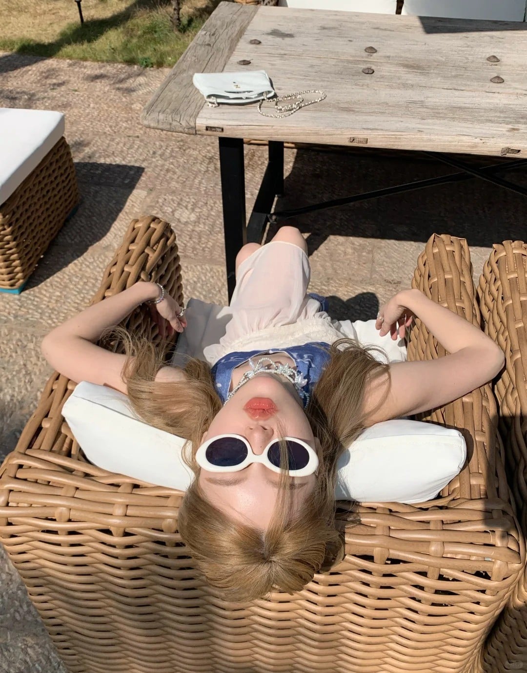 10. Nằm ngửa trên ghế mây (góc chụp từ trên xuống, biểu cảm kiêu kỳ)