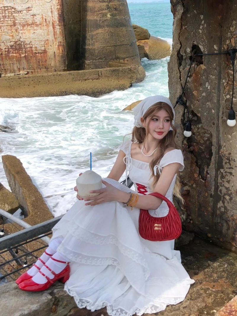 11. Dáng ngồi co chân trên mỏm đá, tay ôm trái dừa