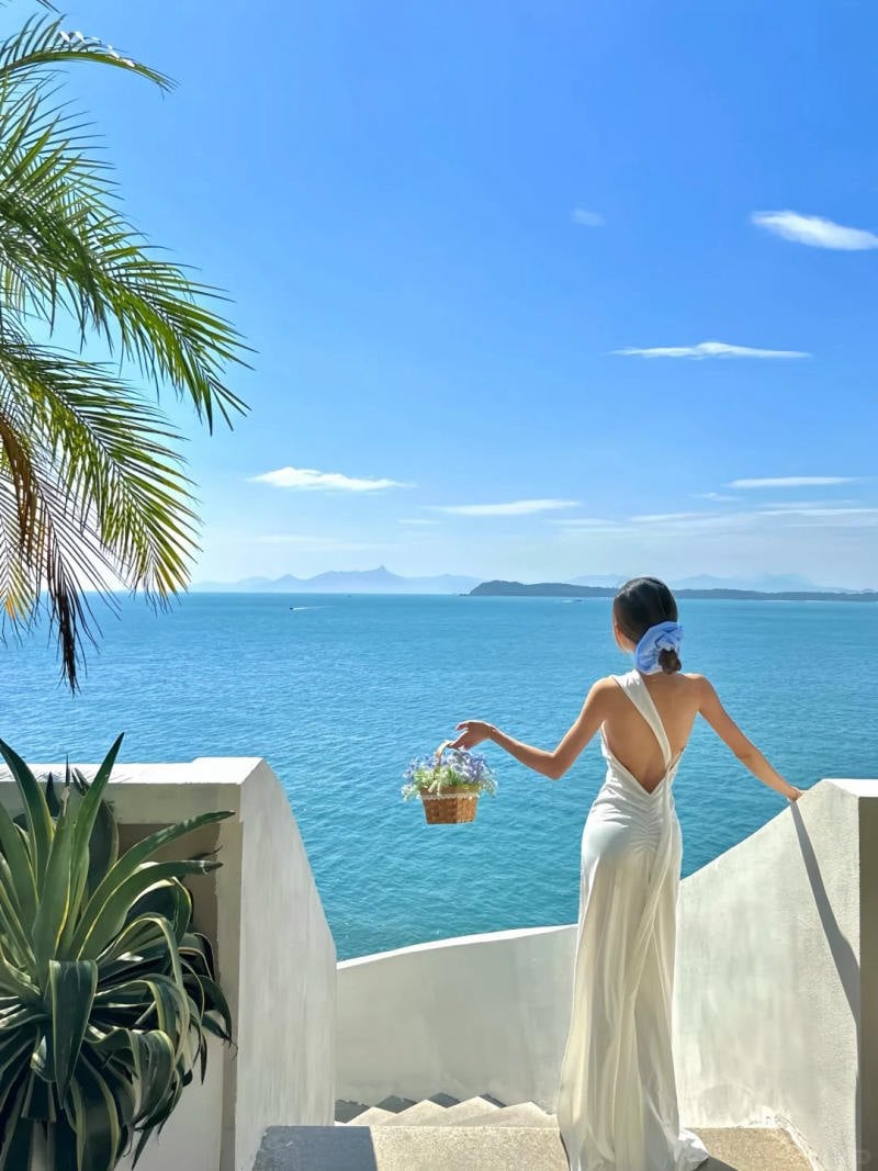 1. Dáng đứng quay lưng, một tay vịn lan can, tay kia xách giỏ hoa