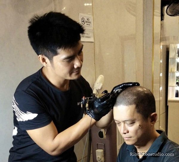 Chuyên viên tại Rio Tattoo Studio đang thực hiện kỹ thuật xăm chân tóc cho khách hàng hói đầu