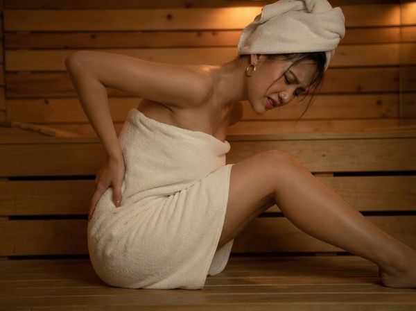 Tư thế ngồi gù lưng gây đau mỏi trong phòng xông hơi khi thiếu tựa lưng.