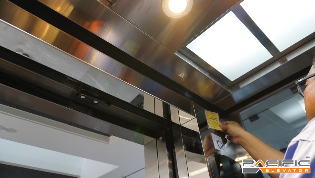 hình ảnh dán tem kiểm định thang máy bàn giao cho khách hàng