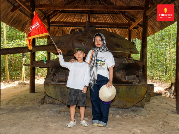 Tourists check in with the remains of a tank while visiting the Cu Chi Tunnels.
