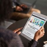 Person holding an iPad with colorful graphics displayed on the screen.