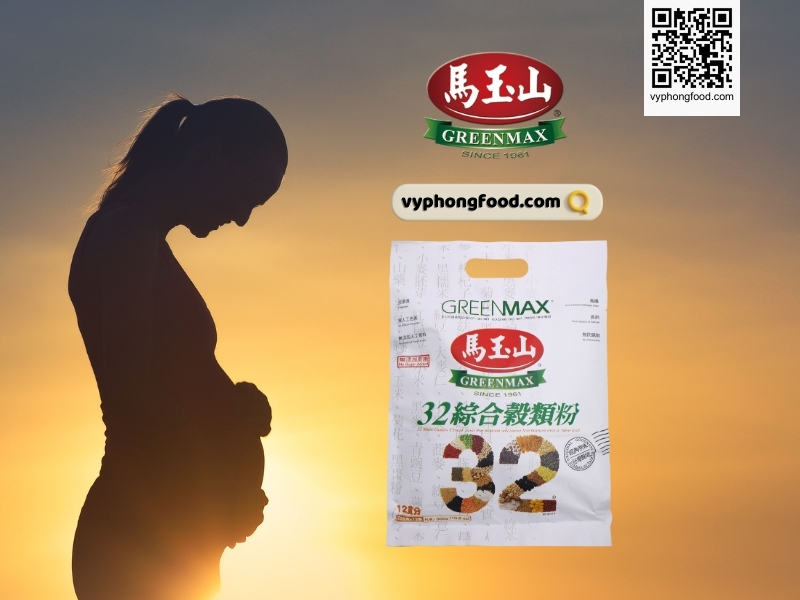 Young pregnant woman sitting at a table reading a prenatal guide about how to drink nutritional cereal powder for pregnant women; Greenmax product guidance and vyphongfood.com branding visible.