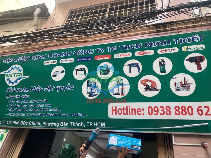 Máy mài góc Makita 9556HN 100mm 840W giơ cao trước bảng hiệu Minh Triết