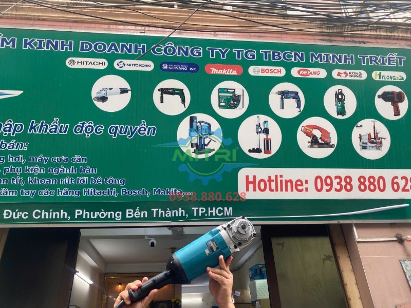 Máy mài góc Makita GA7060 được giơ cao trước bảng hiệu Minh Triết