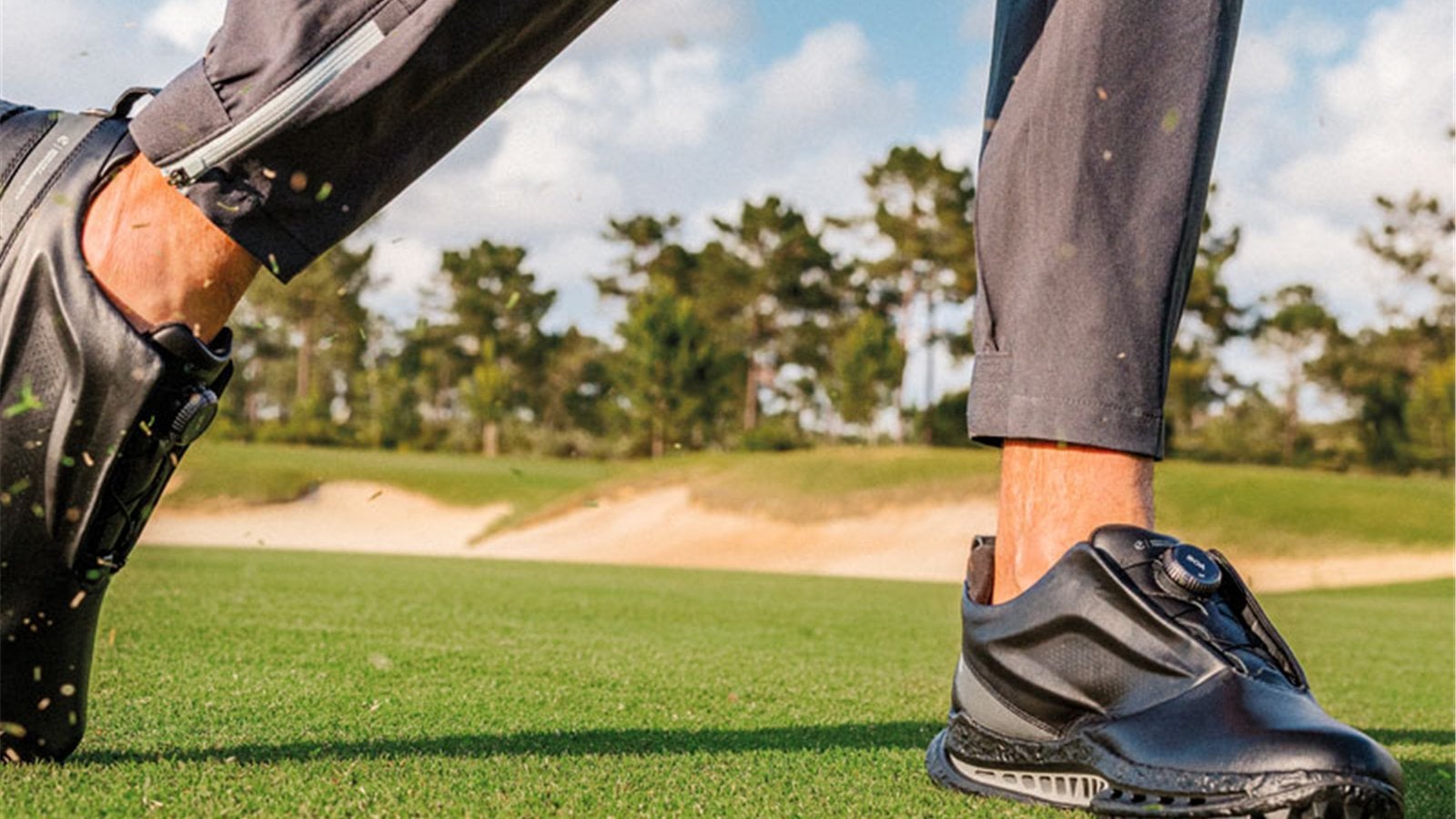 Giày golf đen có núm BOA khi golfer di chuyển gần bunker