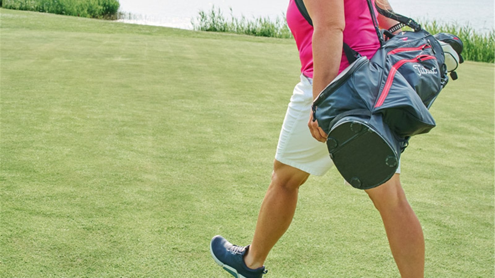 Golfer mang túi gậy và đi bộ trên sân cỏ