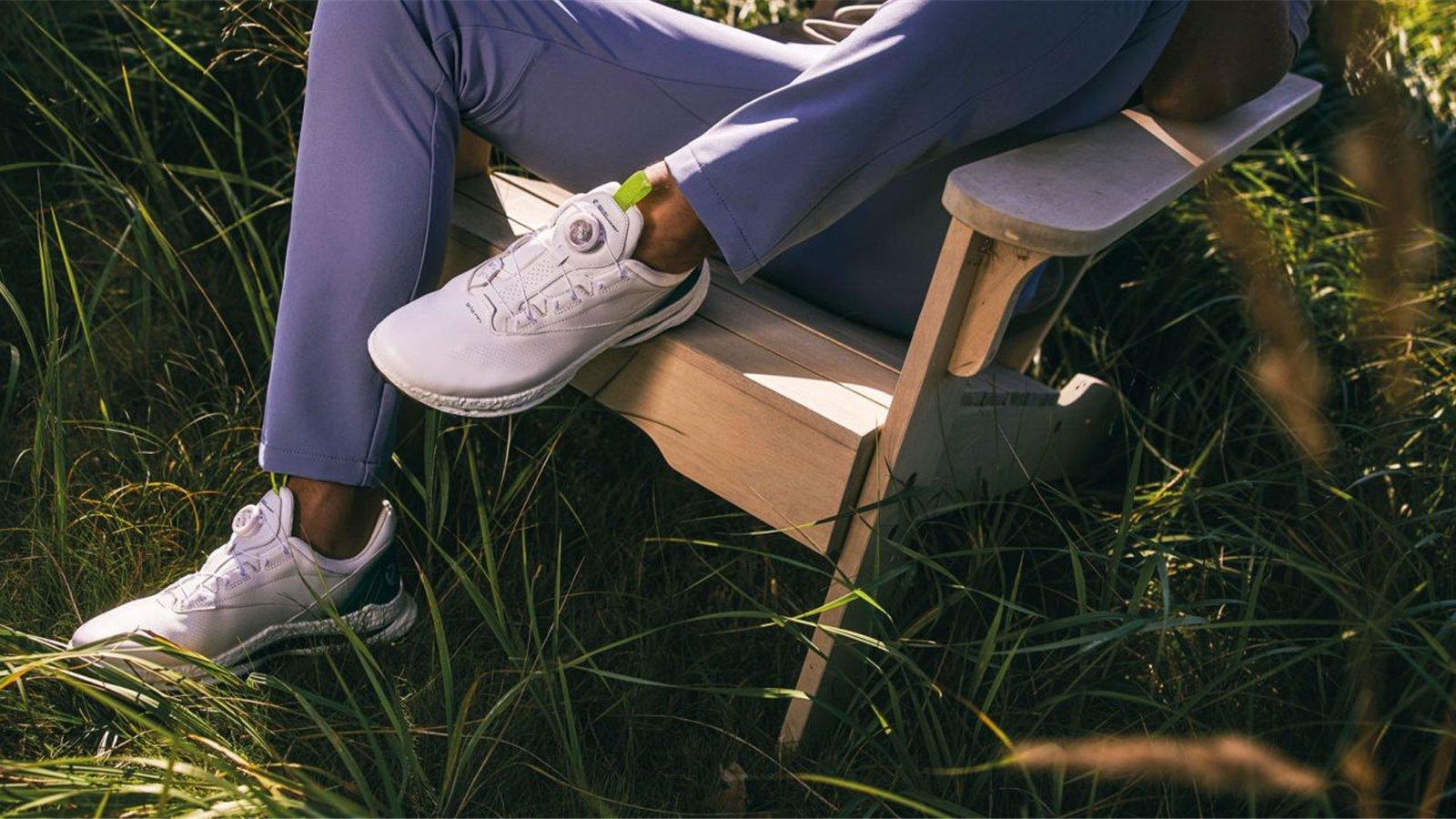 Golfer ngồi trên ghế ngoài trời với giày golf ECCO màu sáng