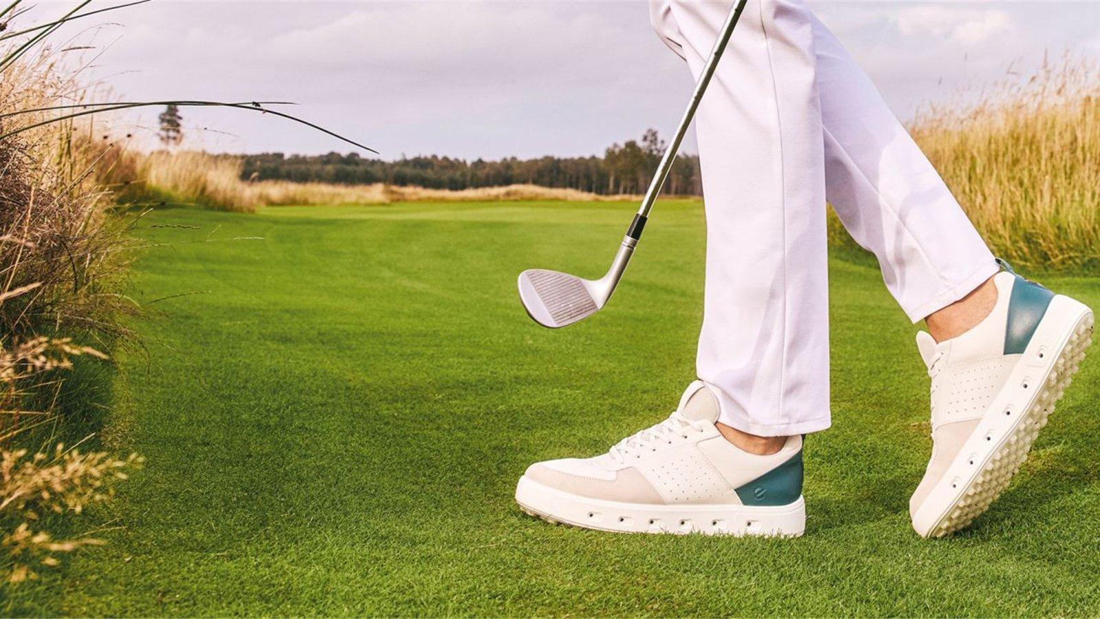 Golfer mang giày golf trắng phối xanh trên fairway