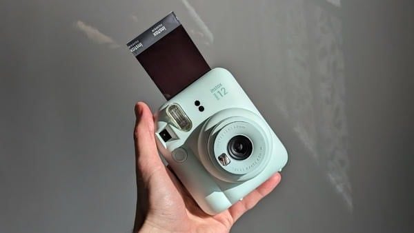 Máy ảnh Instax Mini 12 đang đẩy ảnh in (film) ra ngay sau khi chụp