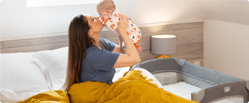 Mum sitting on the floor next to baby in the Joie Serina 2in1 baby swing
